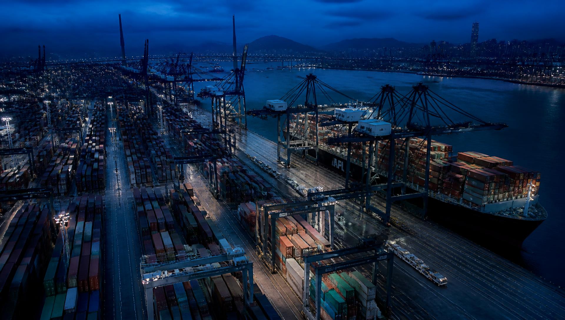 Container ship berthed at a port terminal with gantry cranes at dusk